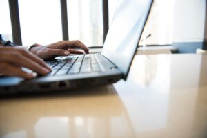 Person using keyboard of laptop, with screen turned to the left.